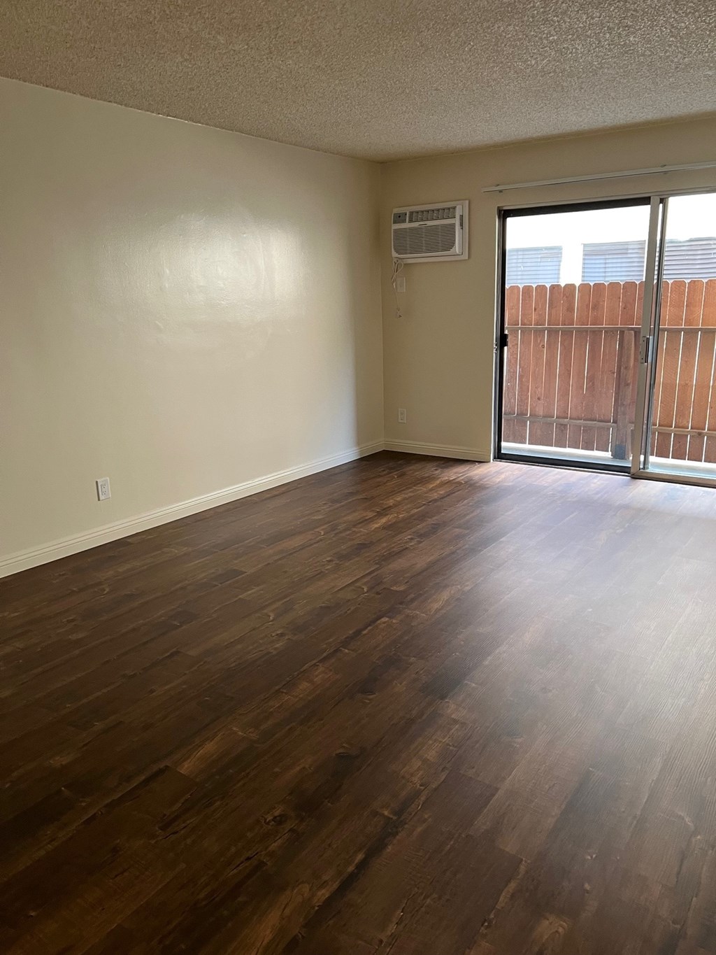 A room with wooden floors and a sliding glass door.