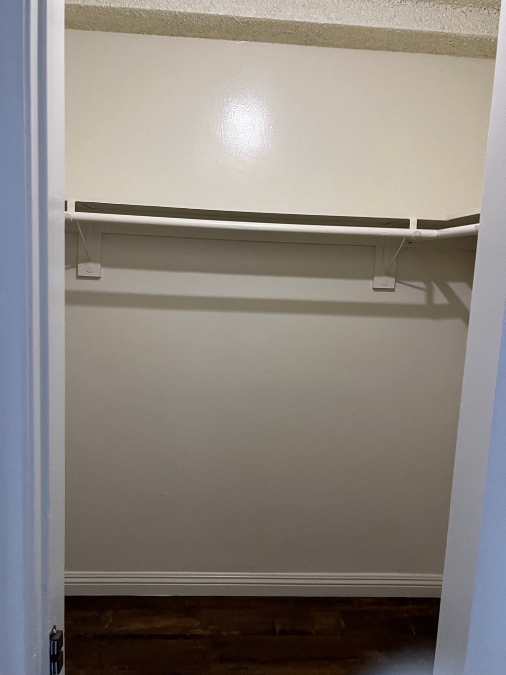 Empty white closet with a shelf and a door.
