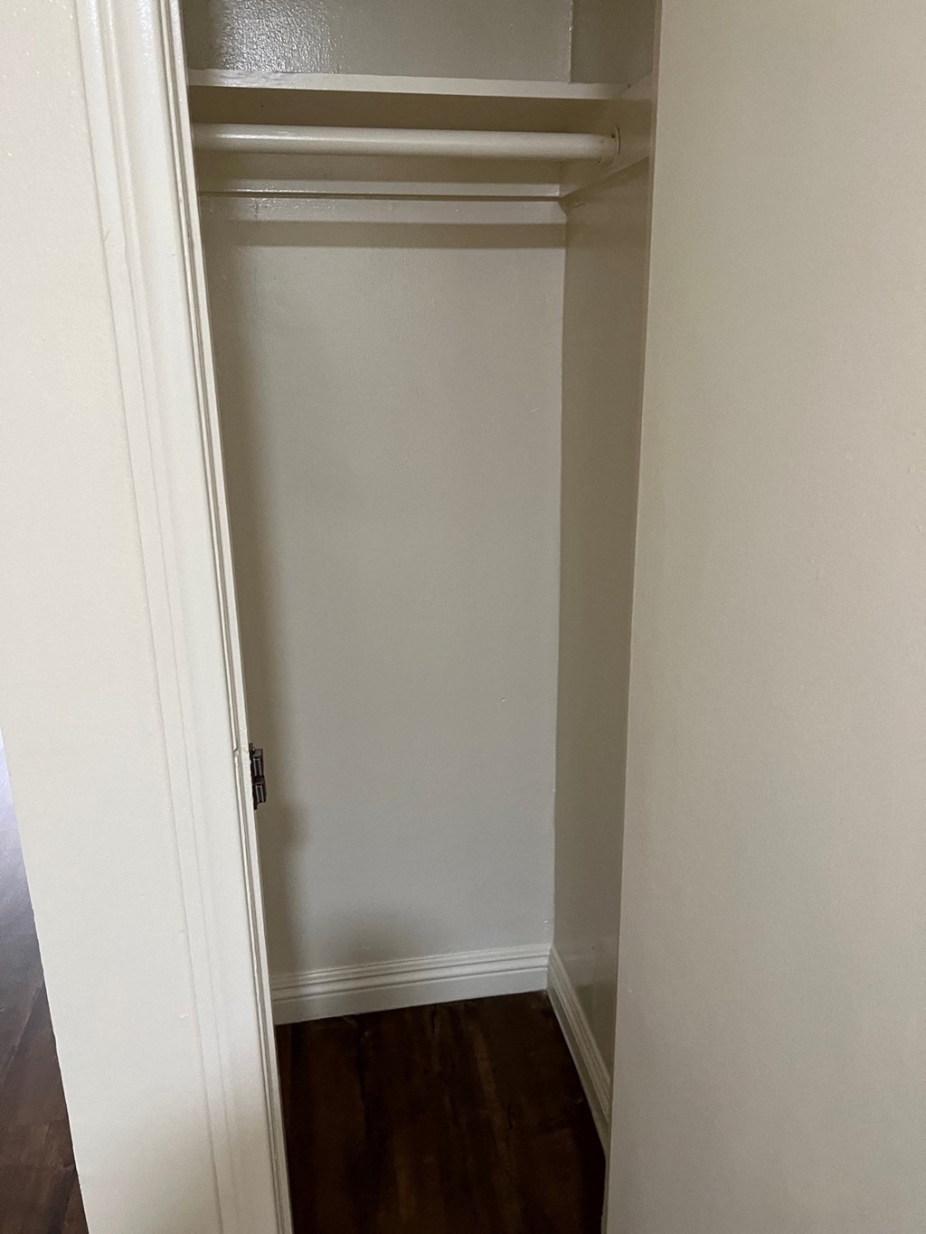 A white door is in a hallway with wood floors.