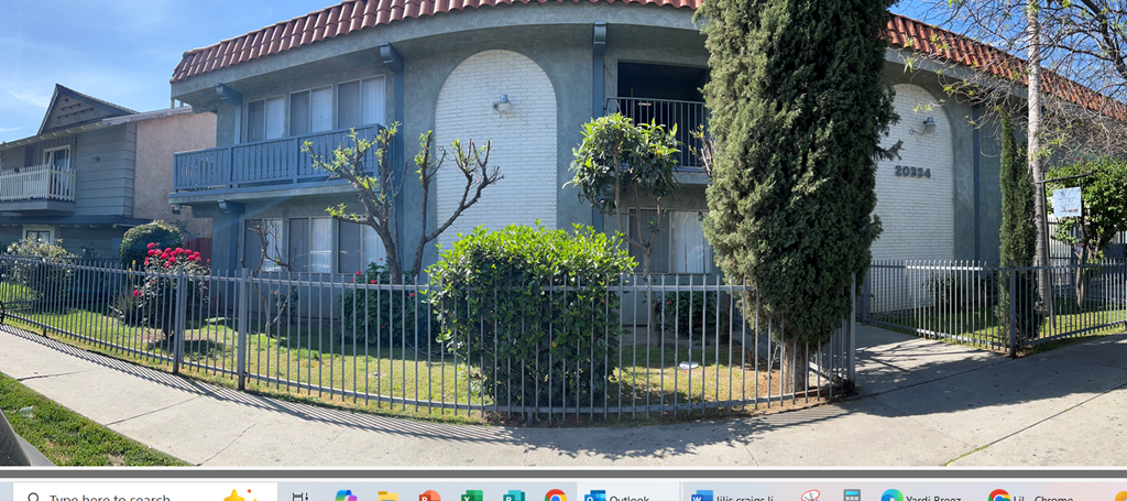 A white house with a red roof and a black fence.