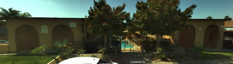 A building with arched doorways and a pool in the yard.