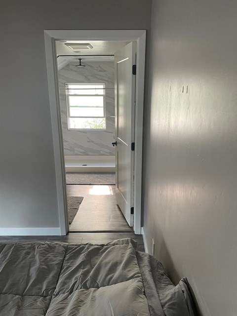 A bedroom with a bed and a door leading to a bathroom.