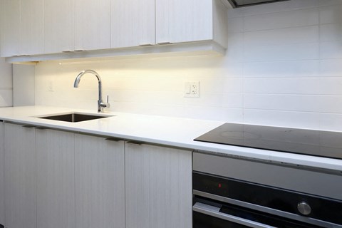 A modern kitchen with white cabinets and a black oven.