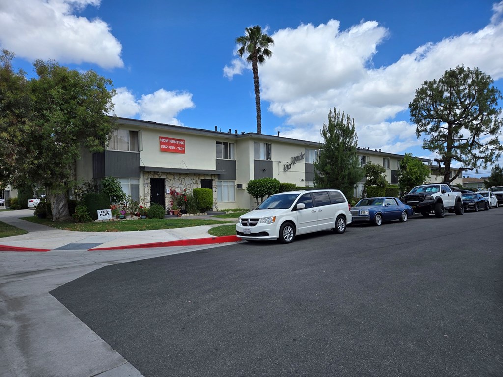 A white van is parked in front of a building with a red sign.