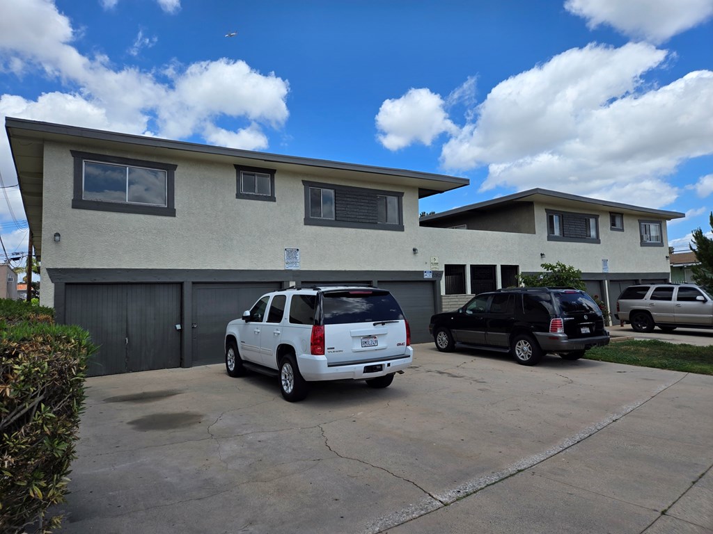 A white SUV is parked in front of a two-story house.