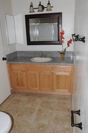 A bathroom with a wooden cabinet and a marble countertop.