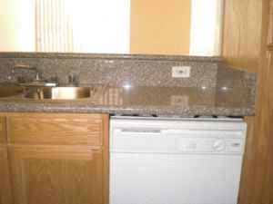A white dishwasher is sitting under a counter with a granite countertop.