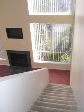 A staircase with a carpeted runner and a window with blinds.