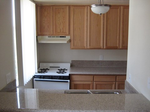 A kitchen with wooden cabinets and a stove top oven.