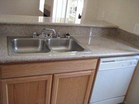 A kitchen with a granite countertop and a double sink.