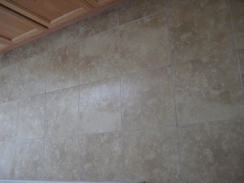 A tile floor with a wooden cabinet above it.
