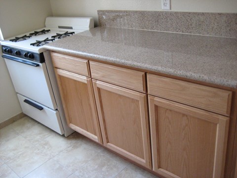 A kitchen with a white stove and wooden cabinets.