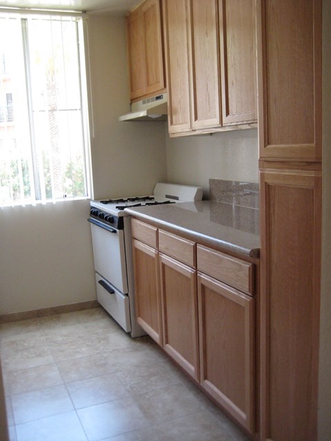 A kitchen with wooden cabinets and a white stove top oven.
