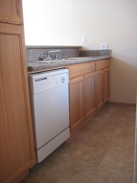 A white dishwasher is in a kitchen with wooden cabinets.