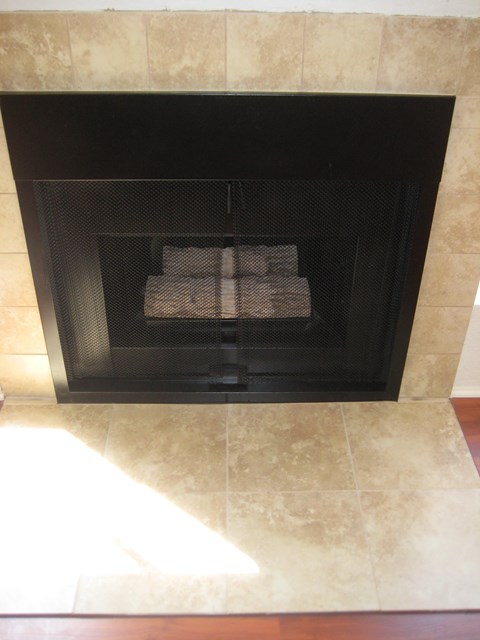 A fireplace with a black grate and a fire inside.