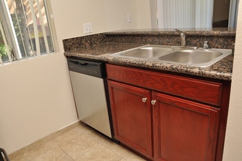 A kitchen with a granite countertop and a double sink.