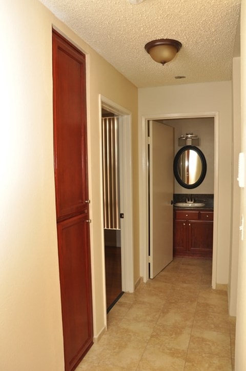A hallway with a brown door and a bathroom visible in the background.