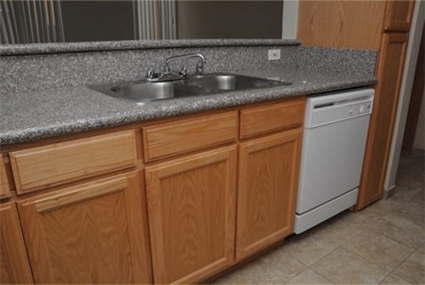 A kitchen with wooden cabinets and a white dishwasher.