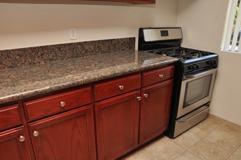 A kitchen with granite countertops and wooden cabinets.