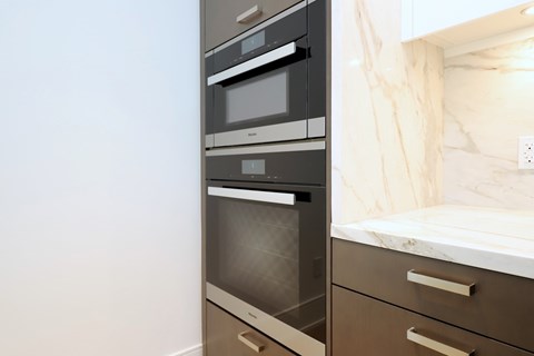 A modern kitchen with a stainless steel oven and a marble backsplash.
