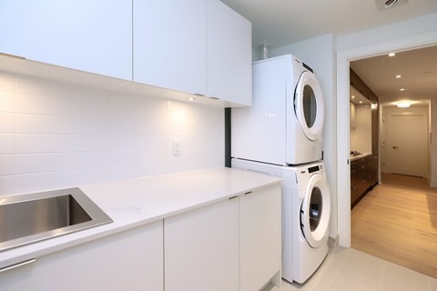 A modern kitchen with white cabinets and a stainless steel sink.