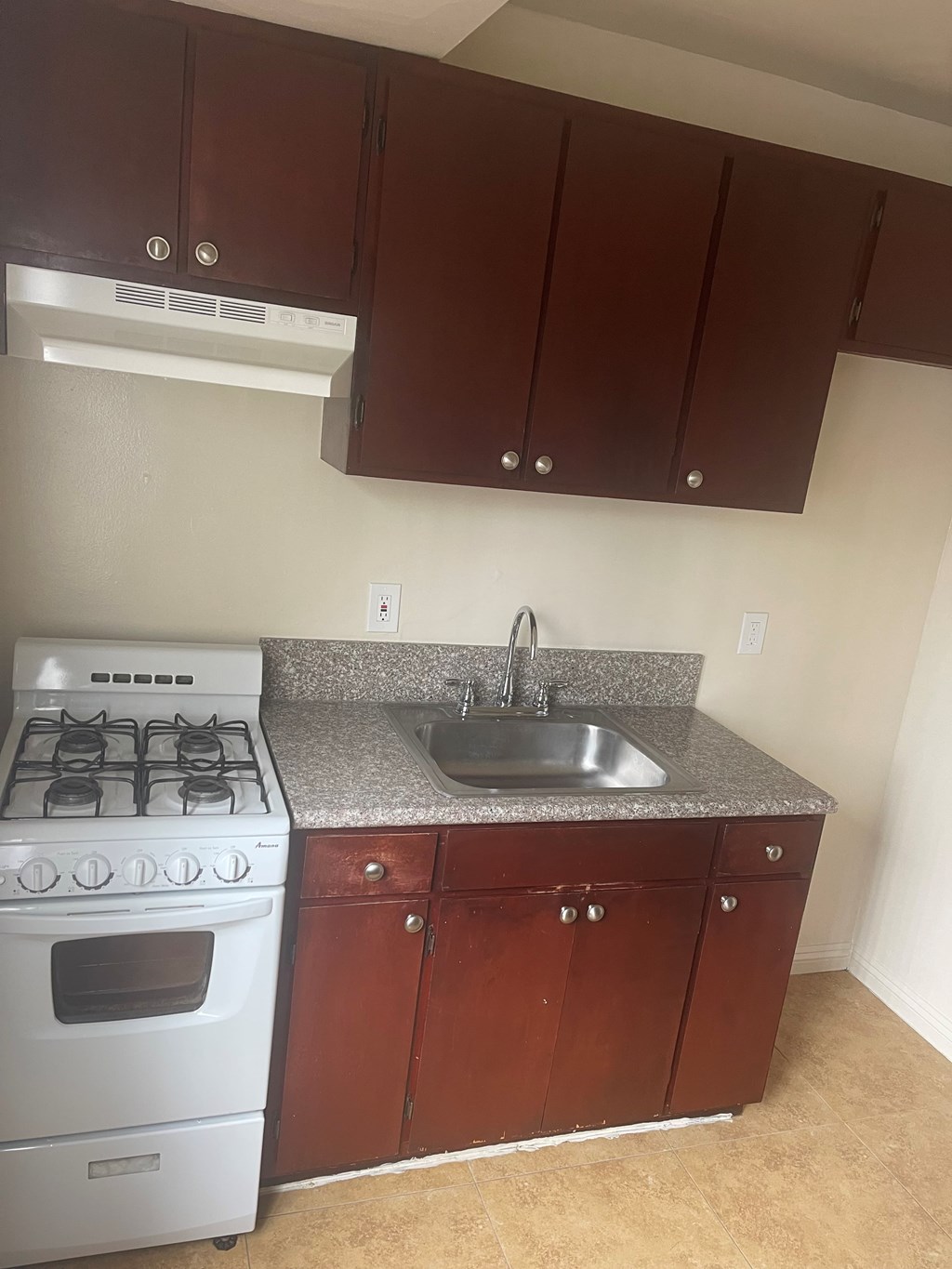 A kitchen with a white stove and brown cabinets.