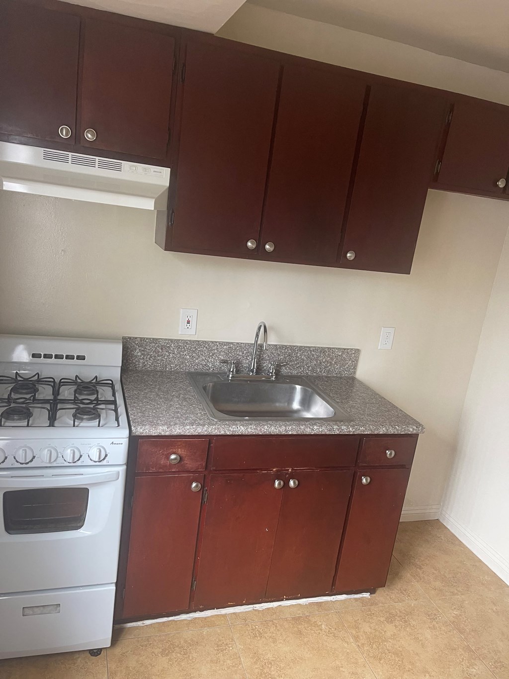 A kitchen with a white stove and brown cabinets.