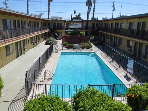 A pool surrounded by a black fence and bushes.