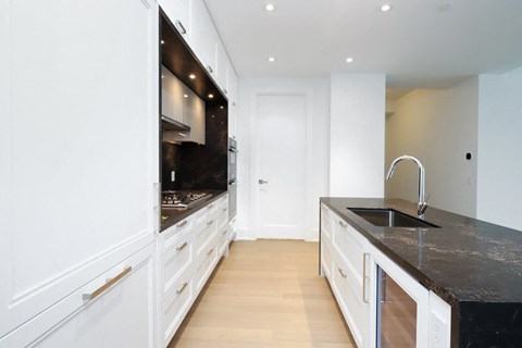 A modern kitchen with white cabinets and a black countertop.