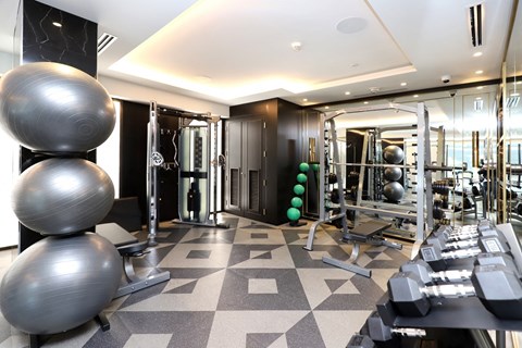 A gym with a variety of equipment including dumbbells, a treadmill, and a weight machine.