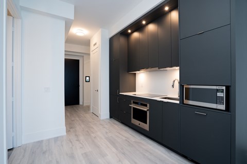 A modern kitchen with dark grey cabinets and a white countertop.