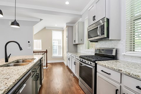 A kitchen with a granite counter top and stainless steel appliances.