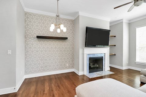 A living room with a fireplace and a television mounted above it.