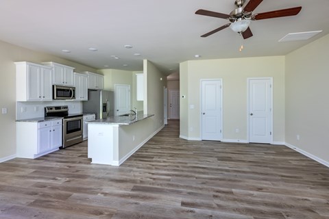 A spacious kitchen with white cabinets and a wood floor.