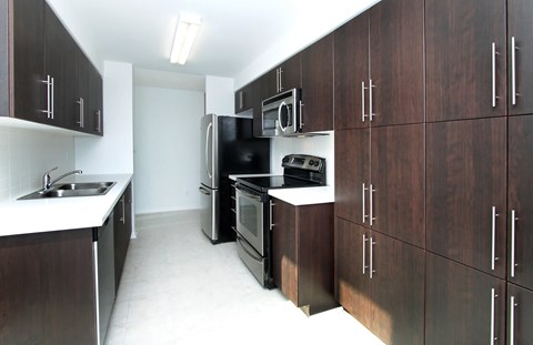 A kitchen with dark wood cabinets and stainless steel appliances.