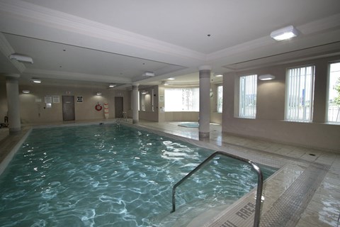 A large indoor swimming pool with a metal ladder on the side.