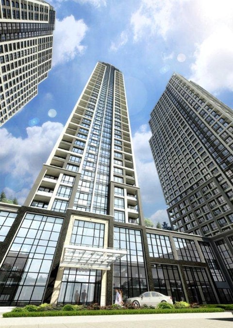 A modern glass building stands tall among other buildings on a sunny day.