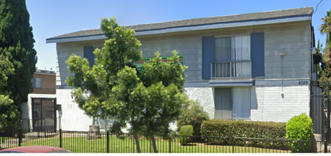 A white house with blue shutters and a black fence.