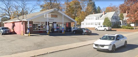 A white car is parked in front of a coffee shop.