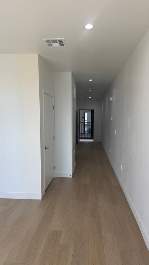 A long hallway with a door on the left and a window on the right.