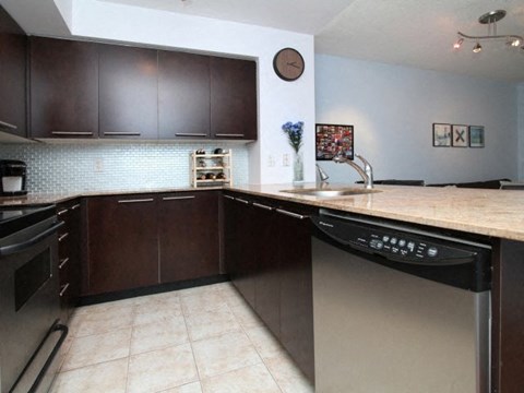 A kitchen with dark brown cabinets and a stainless steel dishwasher.