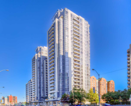 A tall building with many windows is in the middle of a city.