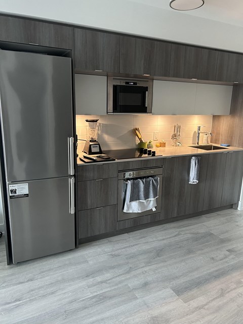 A modern kitchen with a refrigerator, microwave, and a sink.