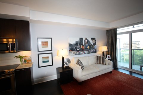A living room with a white couch and a large picture on the wall.