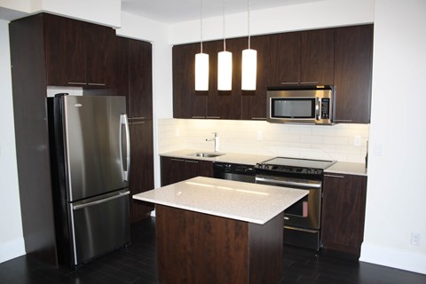 A modern kitchen with dark wood cabinets and stainless steel appliances.