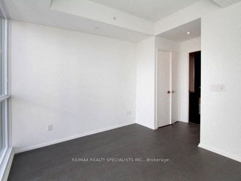A spacious room with white walls and a doorway leading to another room.