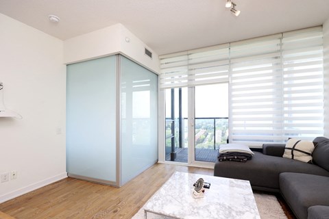 A modern living room with a grey couch and a glass door.