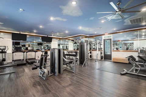 A gym with a variety of equipment including treadmills, weights, and exercise machines.