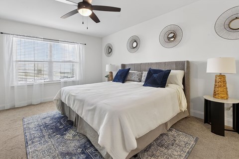 A bedroom with a large bed and a ceiling fan.