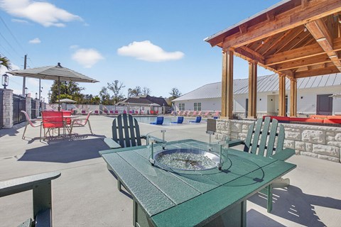 A pool surrounded by red chairs and a striped umbrella.